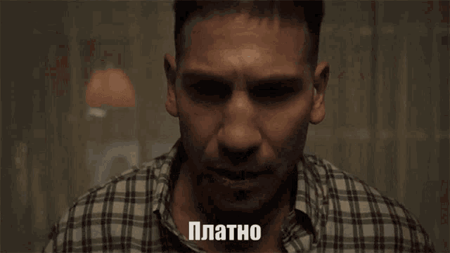 a man in a plaid shirt is looking at his watch and the word platno is on the screen