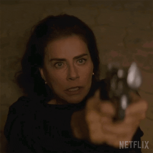a woman is pointing a gun at the camera with a netflix logo in the corner .