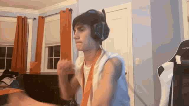 a young man wearing headphones is standing in a room with a chair .