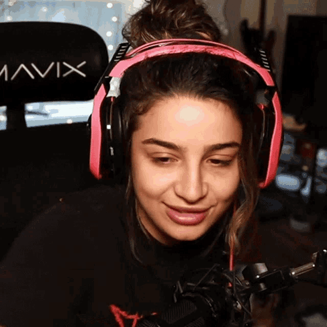 a woman wearing pink headphones is sitting in front of a chair with avix written on it