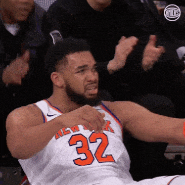 a man in a new york knicks jersey is sitting on the floor