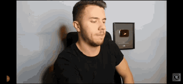 a man in a black shirt is sitting in front of a youtube sign