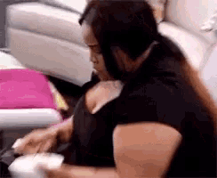 a woman in a black shirt is sitting on a couch eating a meal .