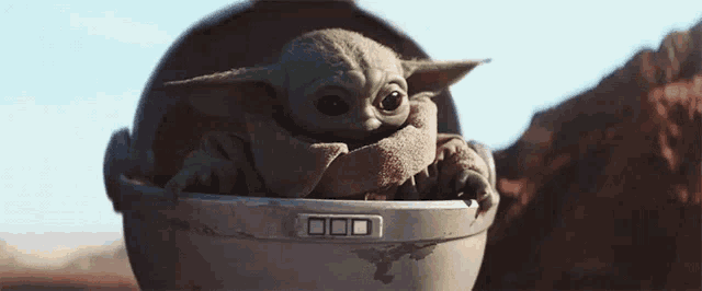a baby yoda is sitting in a stroller on a planet .