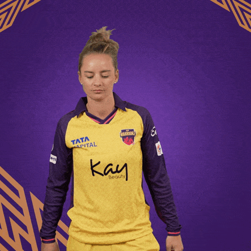 a woman wearing a yellow and purple shirt with the word kay on it