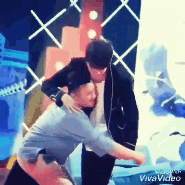 a man in a suit is hugging another man in a blue shirt in a video made by vivavideo