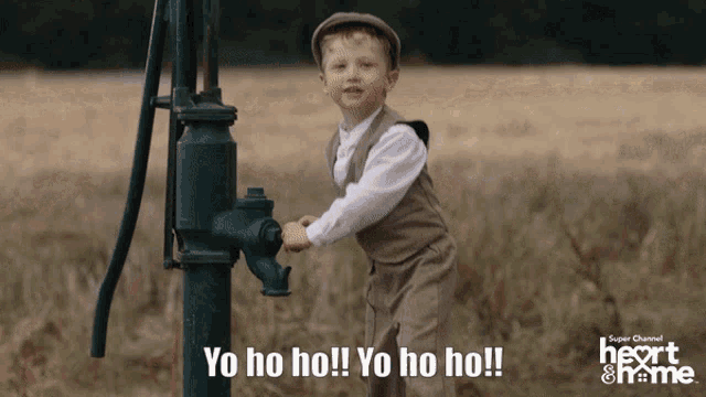 a young boy stands next to a water pump with the words yo ho ho written on it