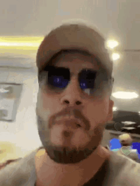 a man with a beard is wearing sunglasses and a baseball cap .