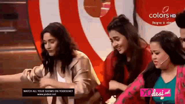 three women are sitting next to each other on a stage in front of a red and white target .