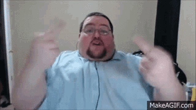 a fat man with glasses and a beard is giving the middle finger while wearing headphones .