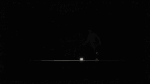 a black and white photo of a person walking in the dark