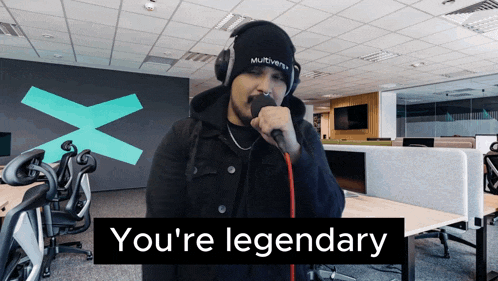 a man singing into a microphone with the words " you 're legendary " behind him