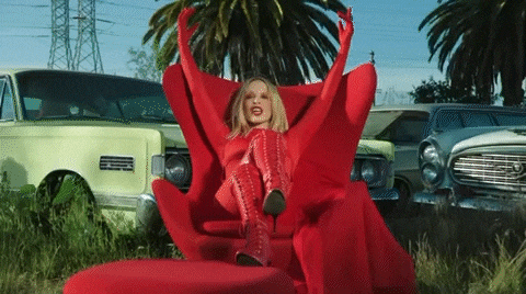 a woman in a red outfit is sitting in a red chair with her arms outstretched