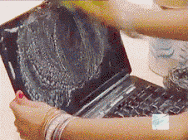 a woman cleaning a laptop with a bottle of cleaner