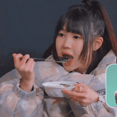 a girl is eating something from a plate with a spoon and a sticker that says hello on it