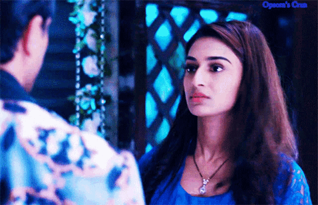 a woman in a blue dress looks at a man in a blue shirt