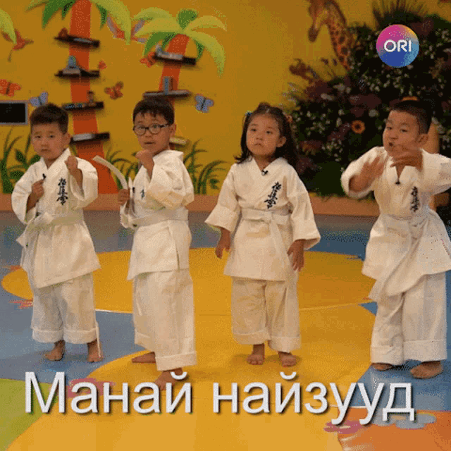 a group of children in karate uniforms are dancing in front of a yellow wall that says ori on it