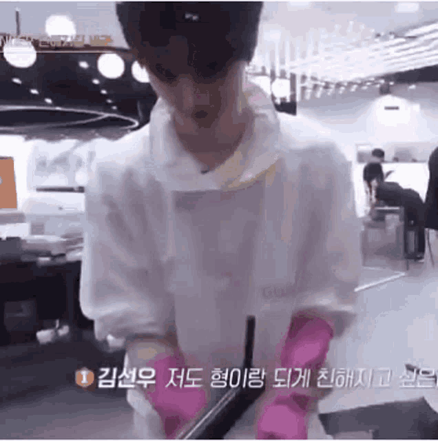 a man wearing pink gloves and a white apron is standing in a kitchen .