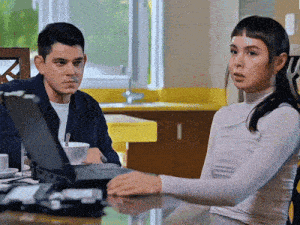 a man and a woman sitting at a table with a laptop