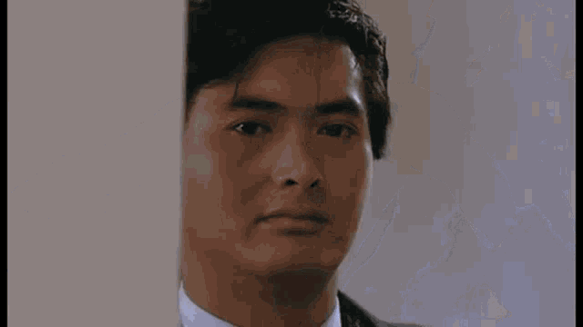 a close up of a man 's face in a suit and tie .