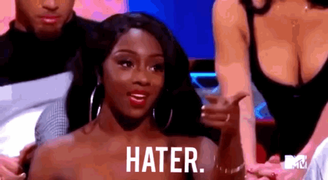 a woman is sitting in front of a group of people with the word hater on her face