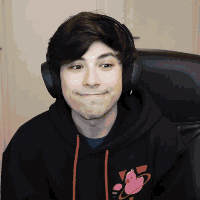 a man wearing headphones and a black hoodie with a pink duck on the front