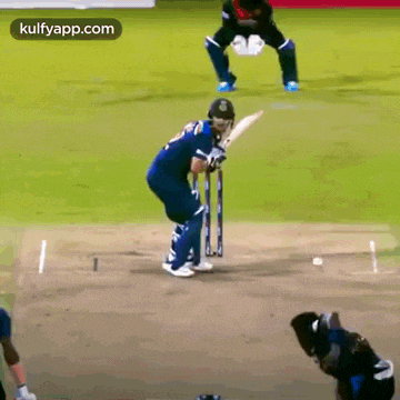 a cricket player is playing a game of cricket on a field while another player watches .