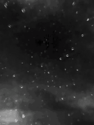 a black and white photo of rain drops falling on a window