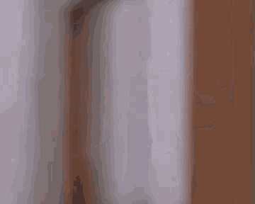 a blurry picture of a man covering his face with his hand while standing next to a wall .