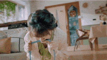 a woman with blue hair is sitting on the floor eating a blue ribbon .