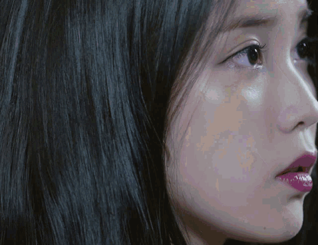 a close up of a woman 's face with black hair and pink lips