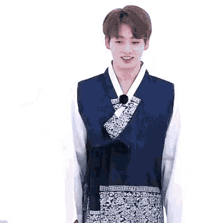 a young man is wearing a traditional korean dress and smiling while standing in front of a white background .