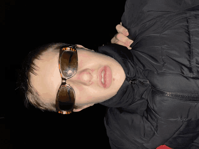 a man wearing sunglasses and a black jacket is laying down