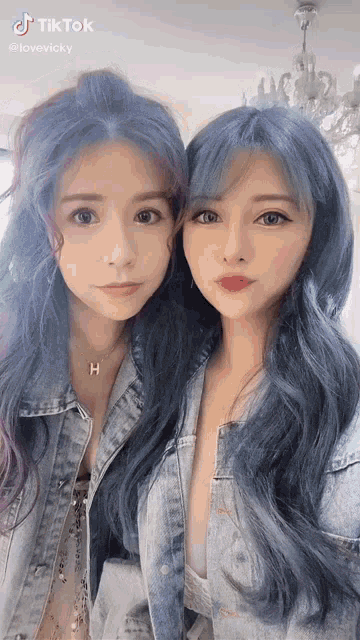 two women with blue hair are standing next to each other .