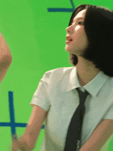 a woman in a white shirt and black tie is standing in front of a green background