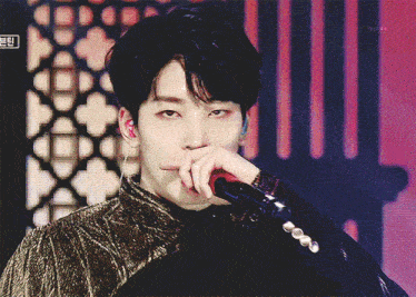 a close up of a person holding a microphone with a foreign language on the bottom left