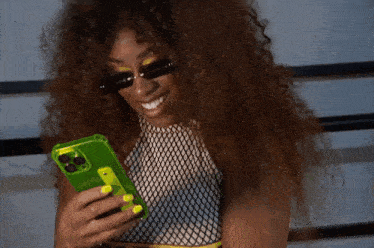 a woman with curly hair is wearing sunglasses and holding a cell phone .