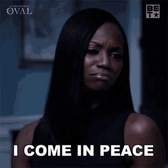 a woman is praying with her hands folded and the words `` i come in peace '' written on her face .