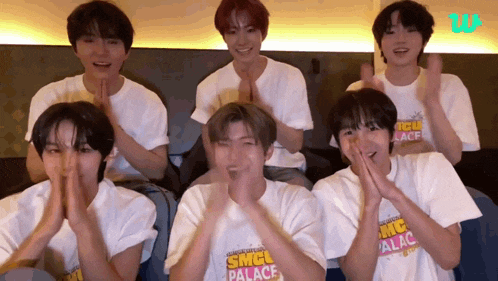 a group of young men wearing white shirts that say sncl palace are clapping their hands .