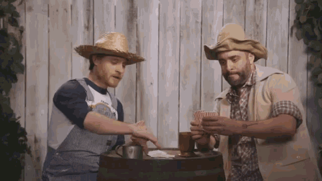 a man wearing overalls and a straw hat is playing cards