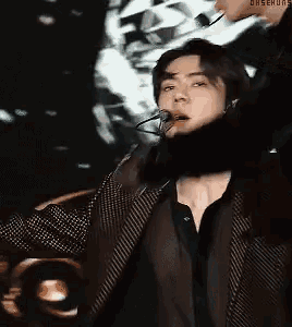 a man is singing into a microphone while wearing a black jacket