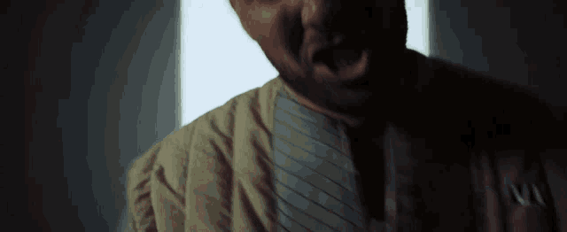 a man with a beard is screaming in a dark room while wearing a jacket with the letter n on it