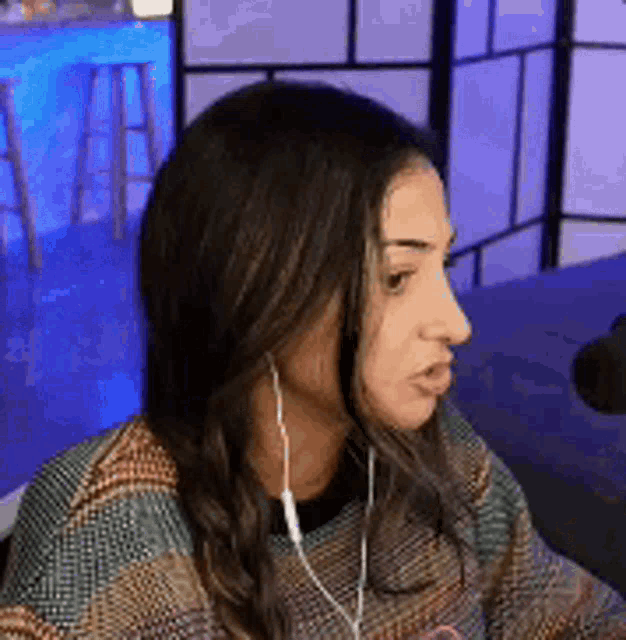 a woman wearing headphones is sitting in front of a microphone in a room .