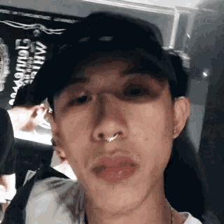 a close up of a man 's face wearing a hat and a nose ring