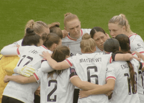 a group of female soccer players huddle together with one wearing the number 12