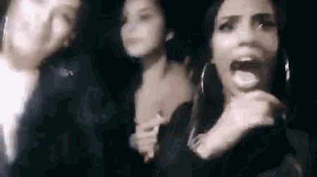 three women are standing next to each other in a dark room .