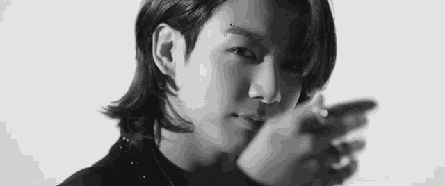 a black and white photo of a young man with long hair and piercings on his face .