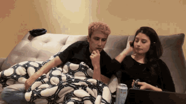 a man and a woman sit on a couch with a can of bud light