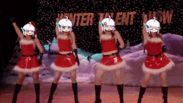 four women in santa outfits are dancing in front of a winter talent show sign