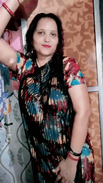a woman in a floral dress stands in front of a wall